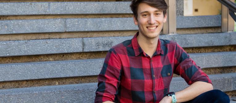 Student sitting on stairs while smiling.
